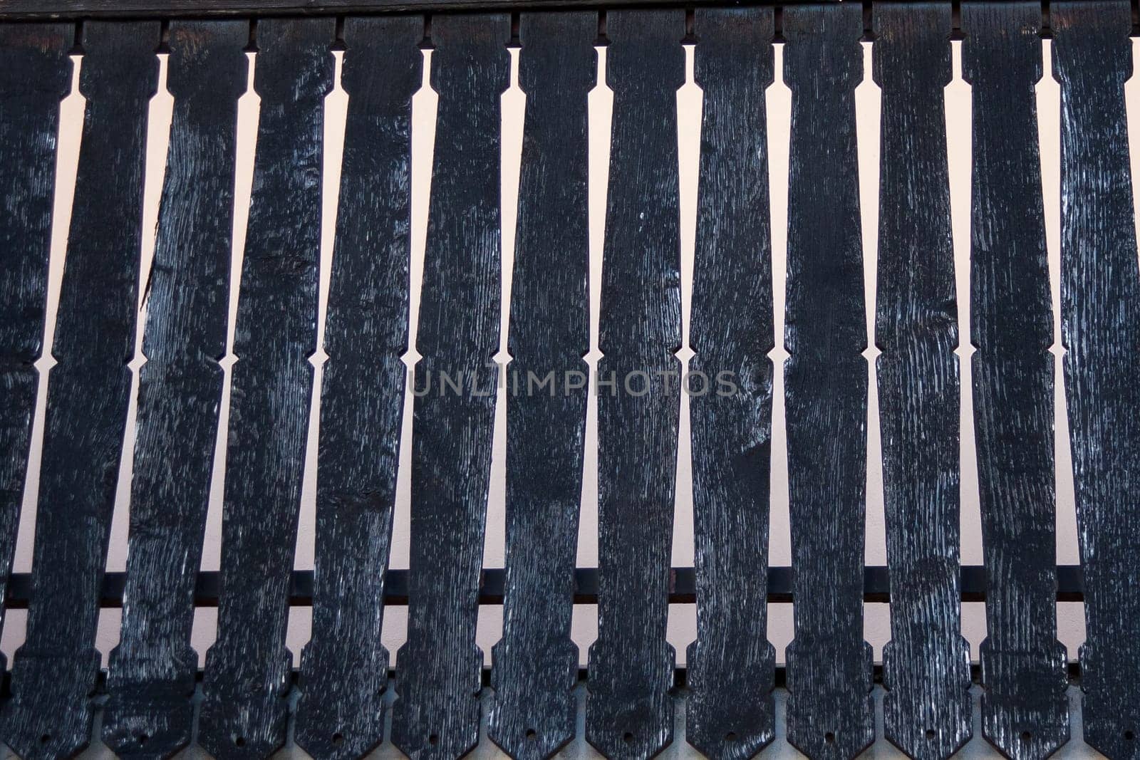Vintage European-style balcony adorned with old, weathered vertical boards painted in a deep black hue.