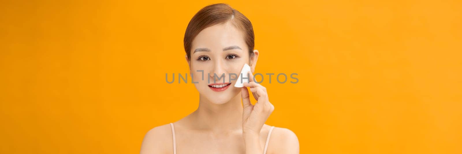Woman Using Cotton Pad Cleansing Face Over banner yellow Background by makidotvn