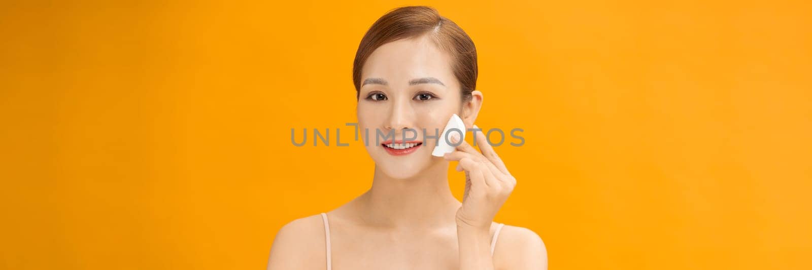 Beauty woman cleaning her face with cotton swab pad isolated on banner background by makidotvn