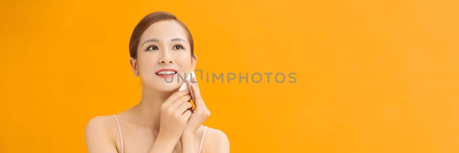 Young healthy woman with beautiful clear skin holding cotton pads on banner background by makidotvn