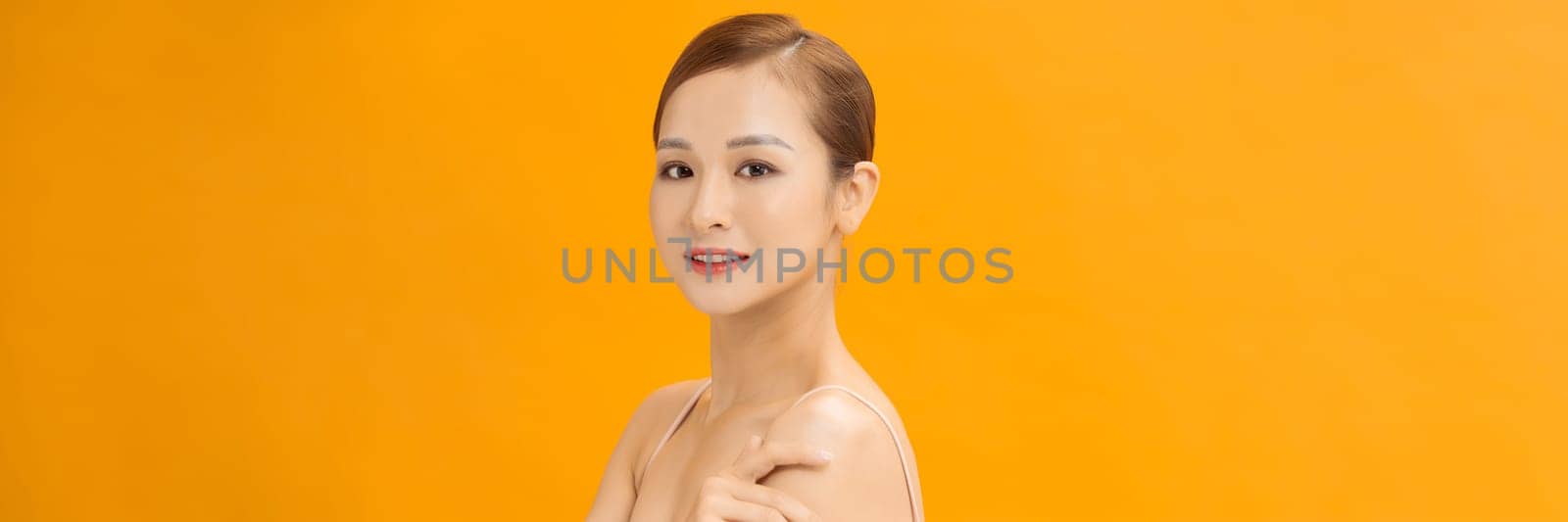 Youthful smiling Asian woman isolated on yellow banner background for beauty and skin care concepts by makidotvn