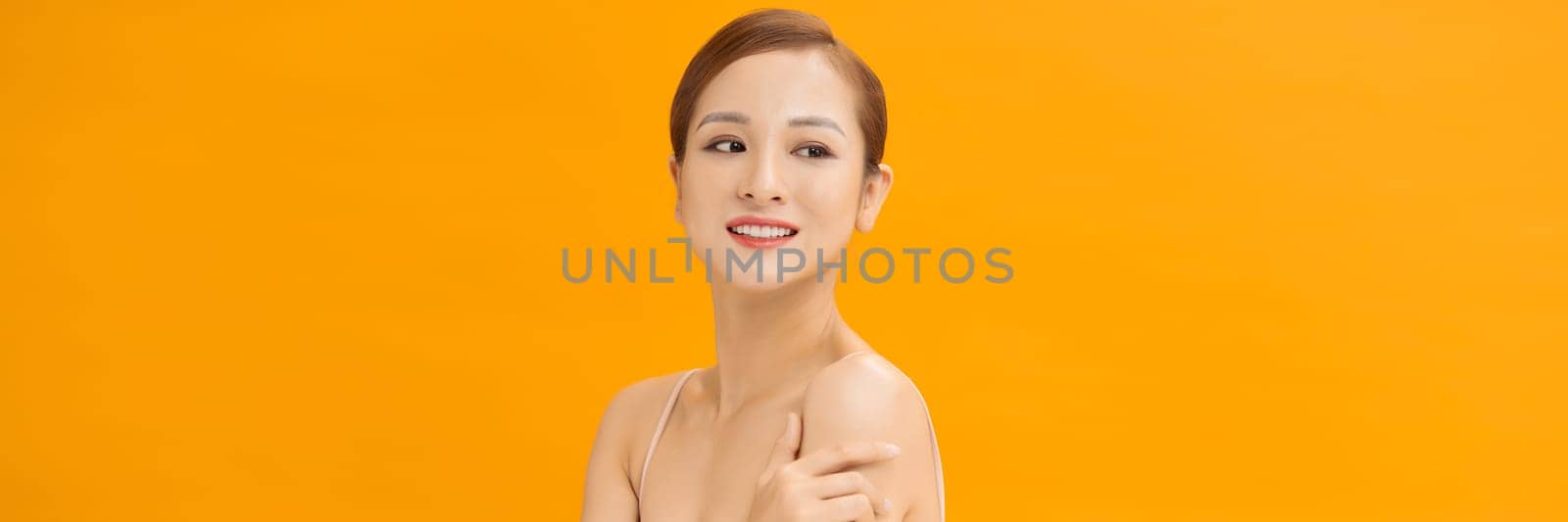 Youthful smiling Asian woman isolated on yellow banner background for beauty and skin care concepts by makidotvn