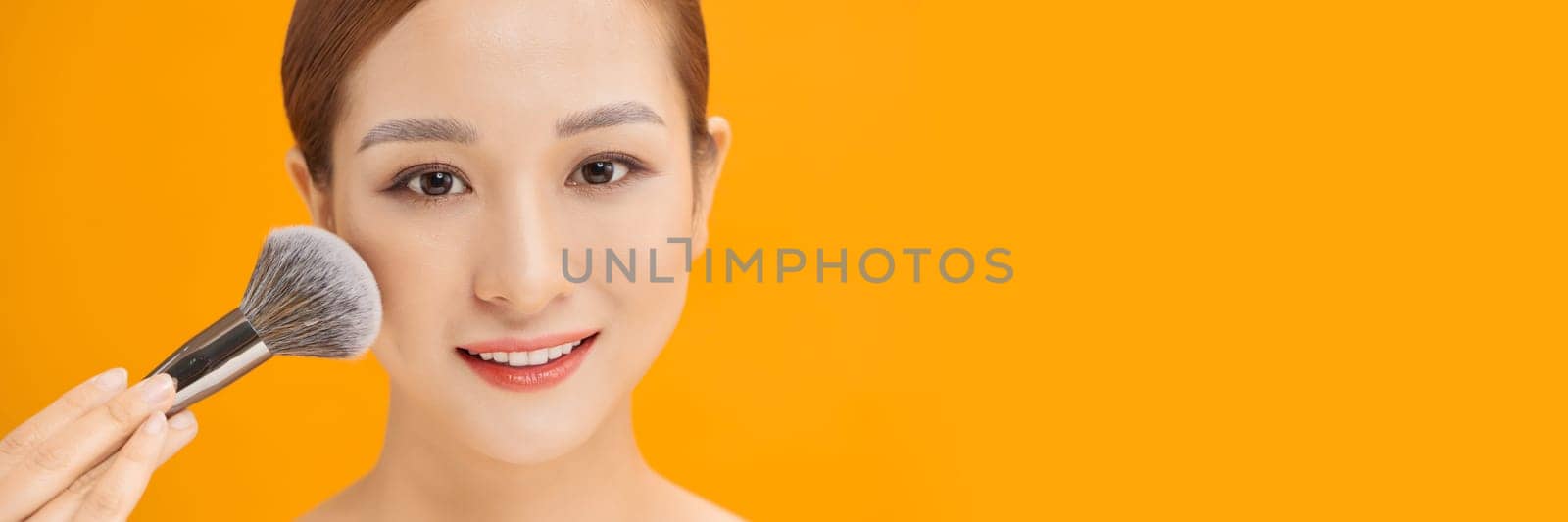 Attractive beautiful girl get natural makeup by using brush makeup on banner background by makidotvn