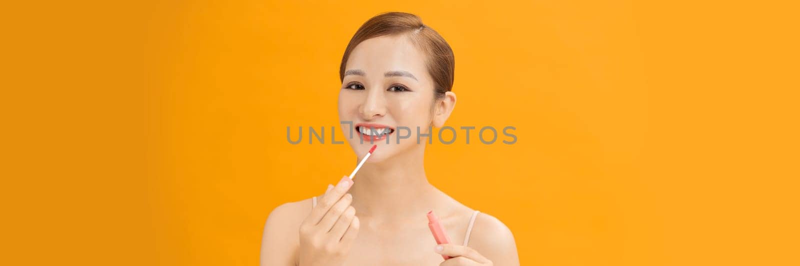 Web banner of young woman applies lipstick on lips.  by makidotvn