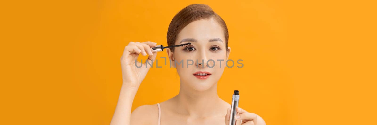 Banner of pretty young woman applying mascara using lash brush