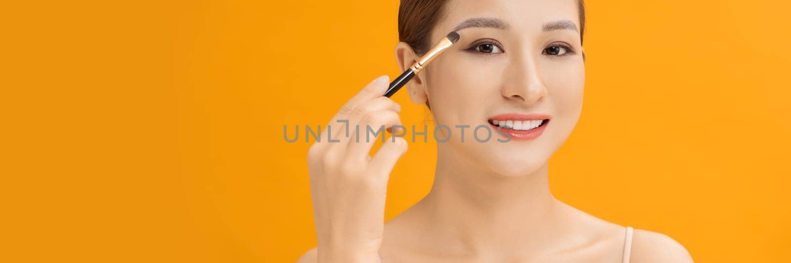 woman applying eyeshadow on eyelid using makeup brush. Web banner. by makidotvn