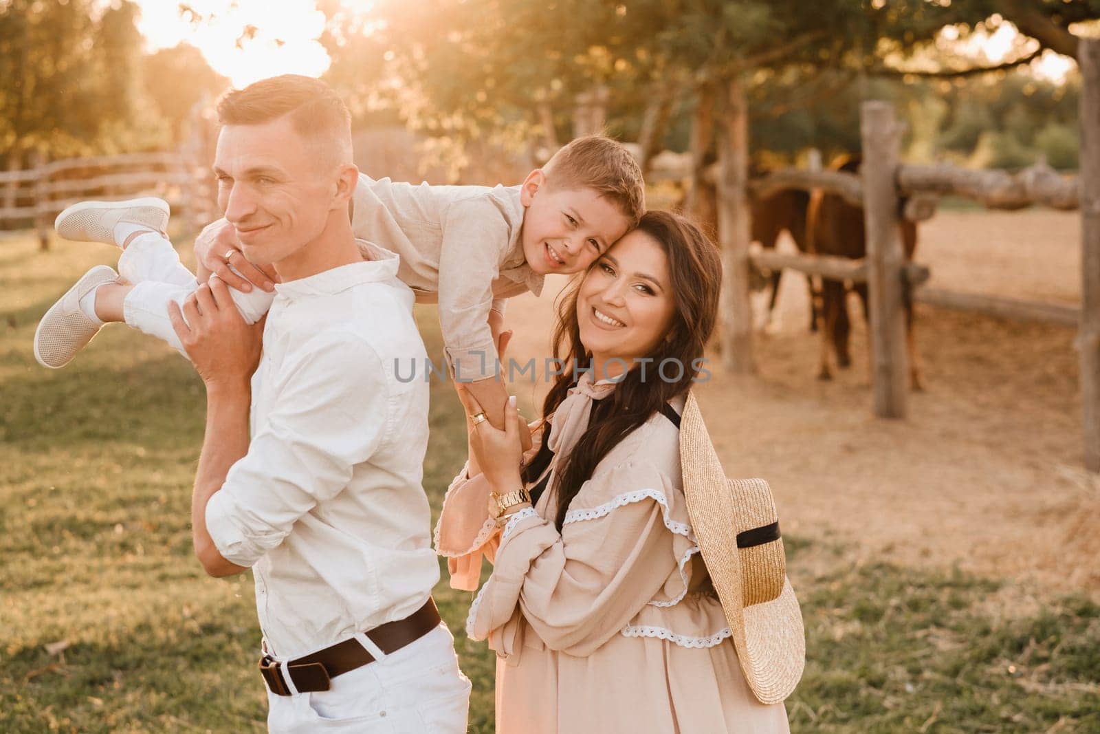 A stylish family in the countryside at sunset. A pregnant woman with her husband and son in nature.