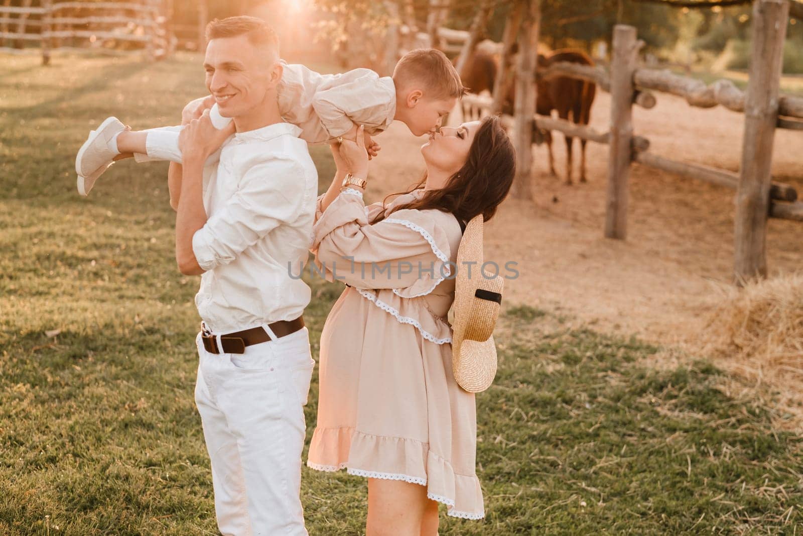 A stylish family in the countryside at sunset. A pregnant woman with her husband and son in nature.