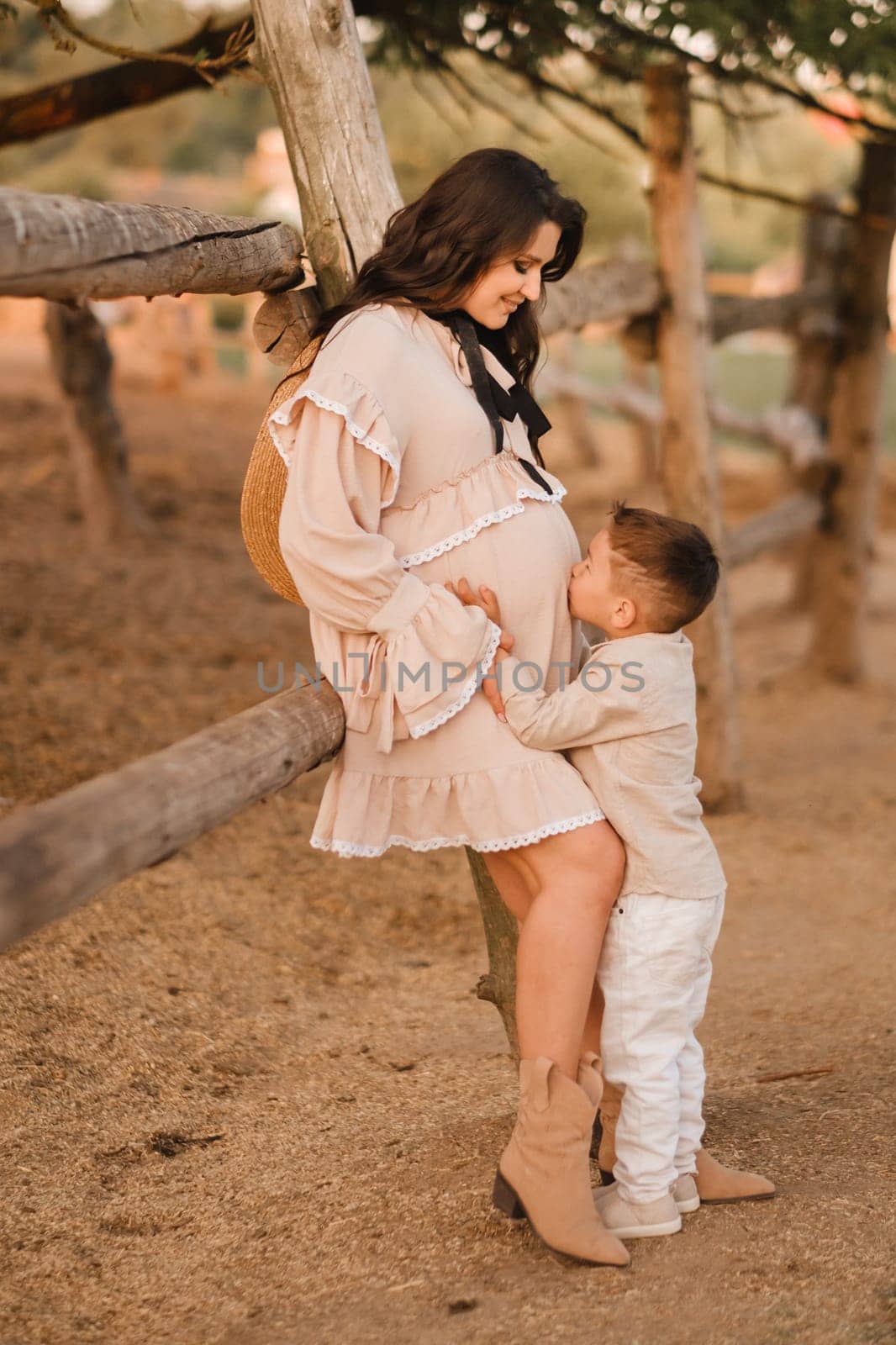 A pregnant woman with her son walks in the countryside in the summer.