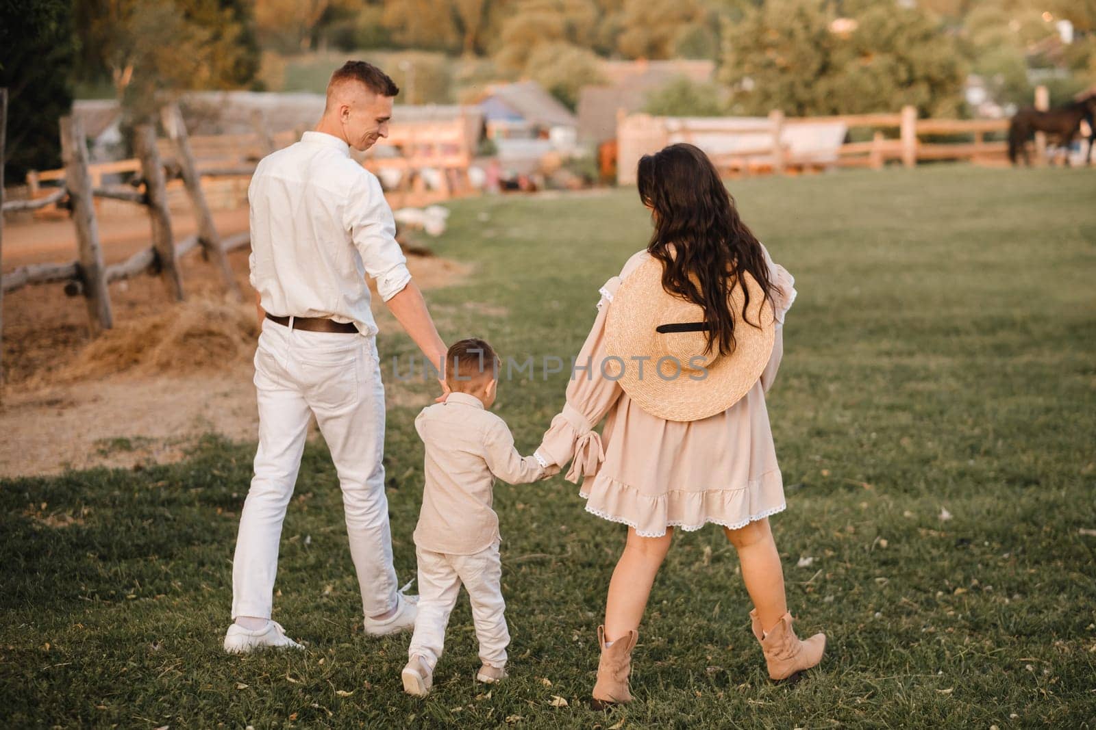 A stylish family in the countryside at sunset. A pregnant woman with her husband and son in nature by Lobachad