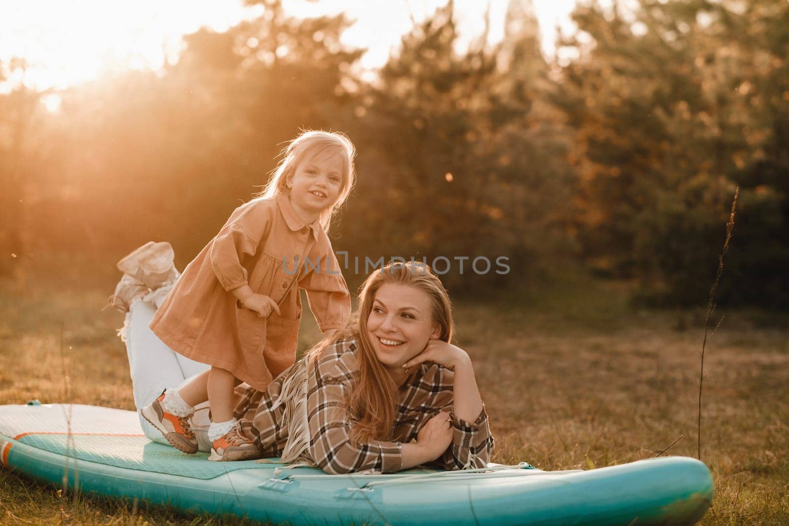 Mom and daughter on a sup board in the forest at sunset.