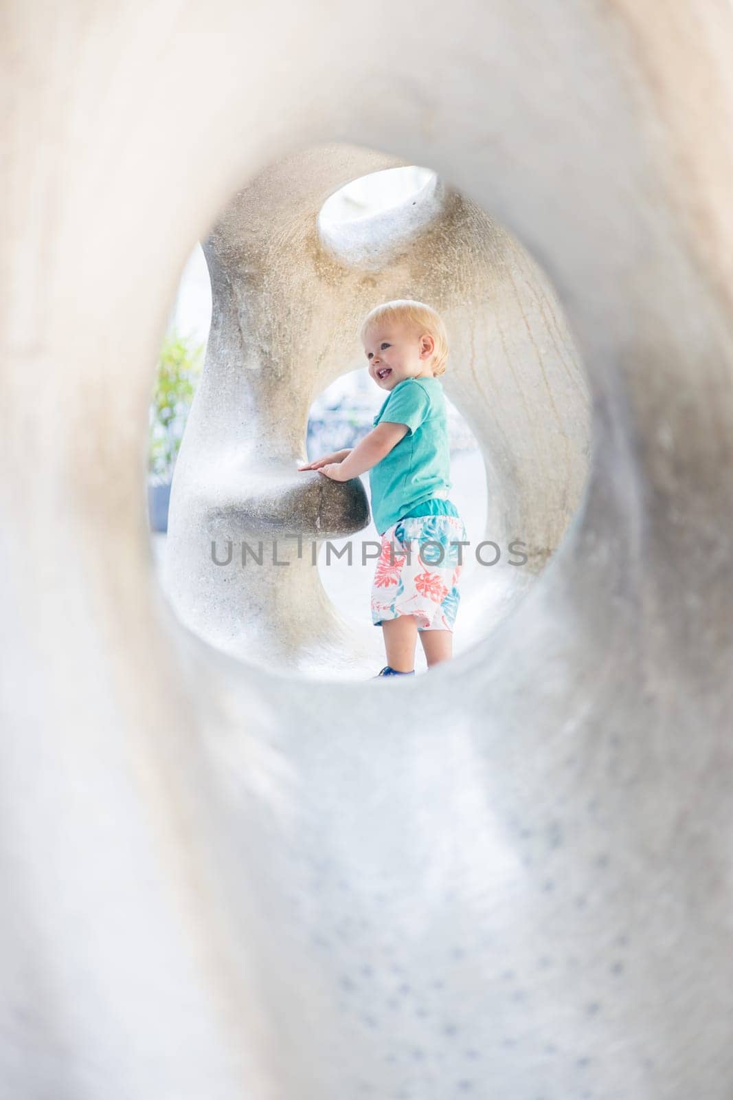 Child playing on outdoor playground. Toddler plays on school or kindergarten yard. Active kid on stone sculpured slide. Healthy summer activity for children. Little boy climbing outdoors. by kasto