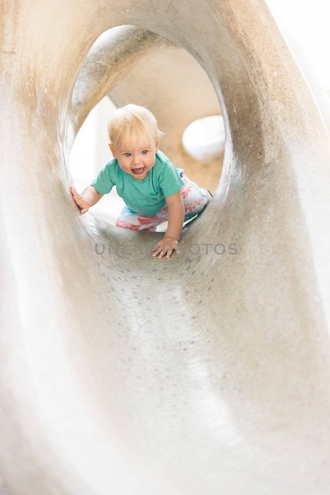 Child playing on outdoor playground. Toddler plays on school or kindergarten yard. Active kid on stone sculpured slide. Healthy summer activity for children. Little boy climbing outdoors