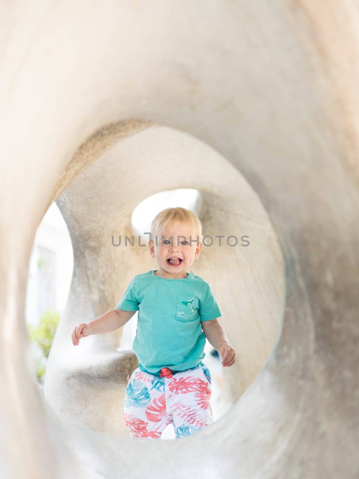 Child playing on outdoor playground. Toddler plays on school or kindergarten yard. Active kid on stone sculpured slide. Healthy summer activity for children. Little boy climbing outdoors