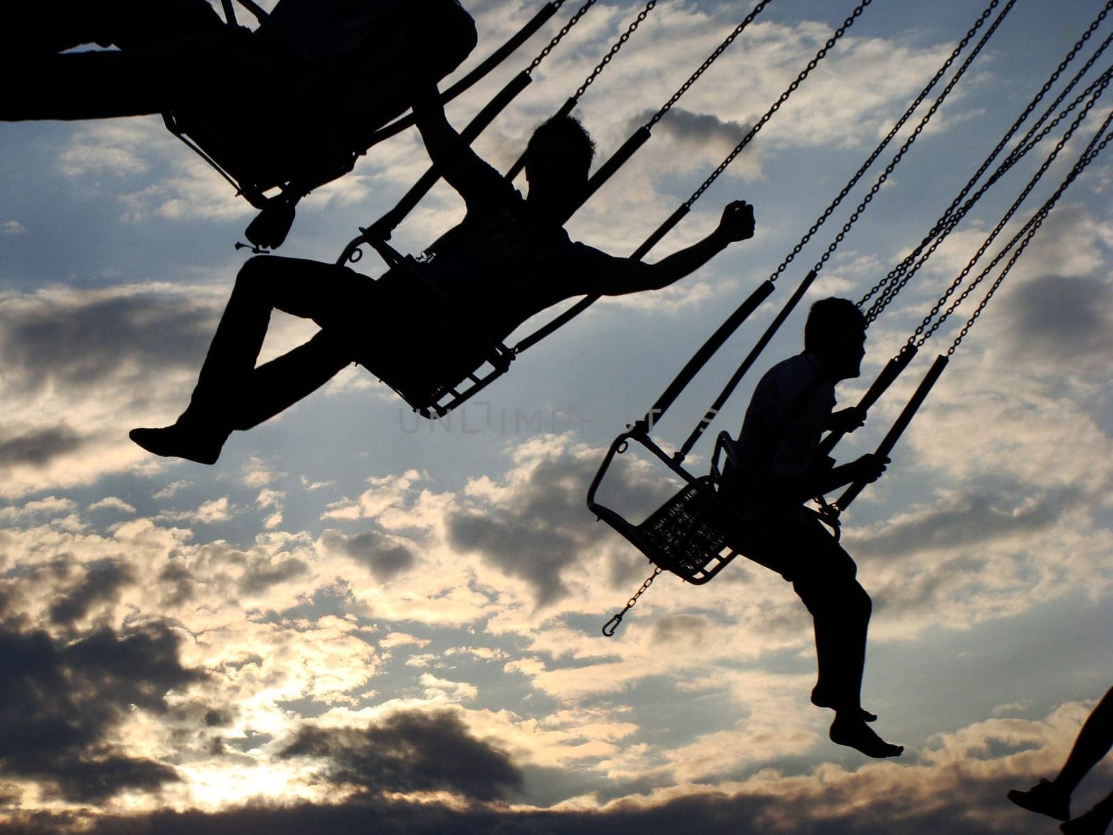 People ride on a carousel. Silhouettes of people riding on a carousel at sunset. High quality photo