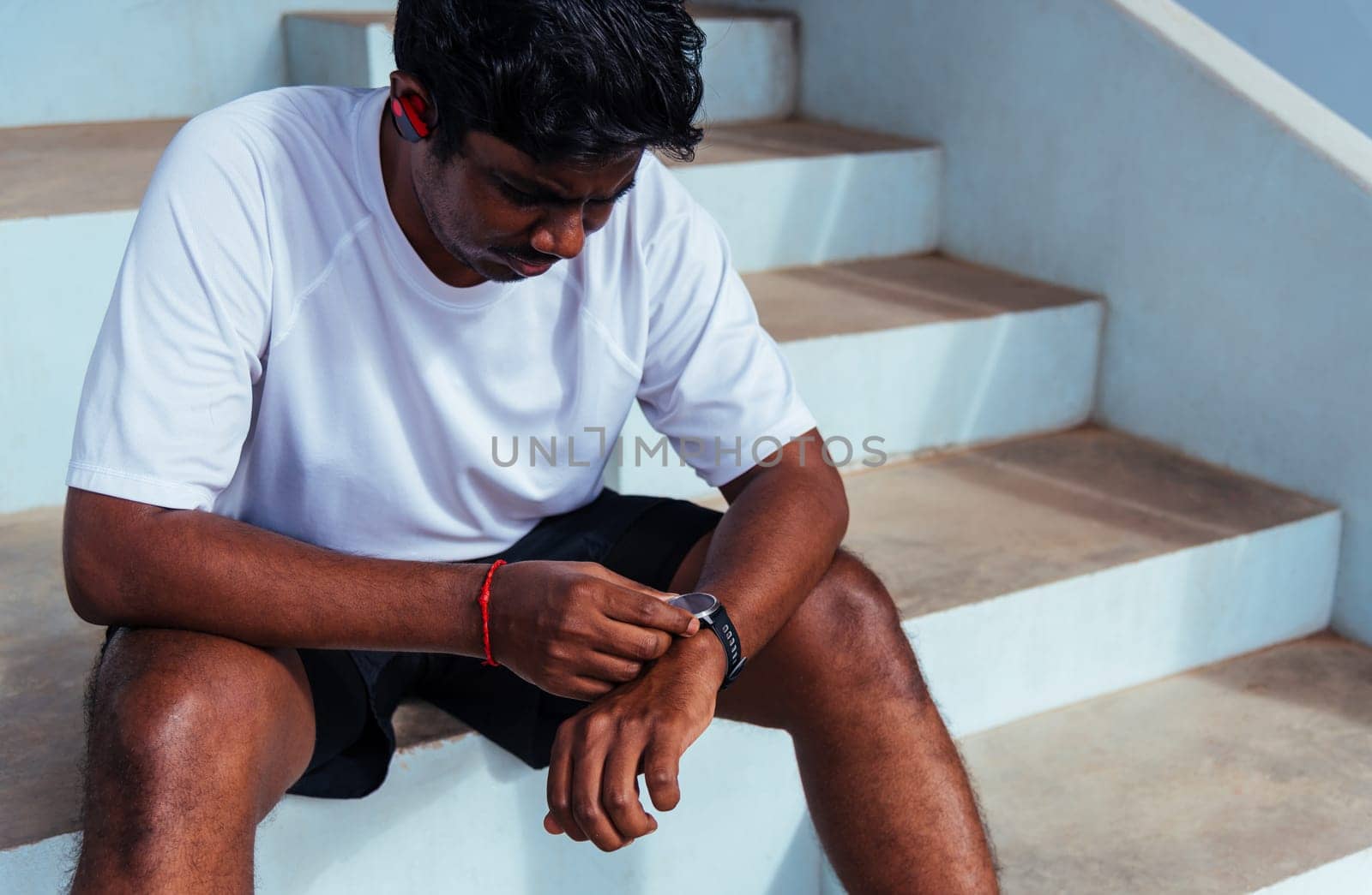 sport runner black man wear modern time smart watch he sitting resting by Sorapop