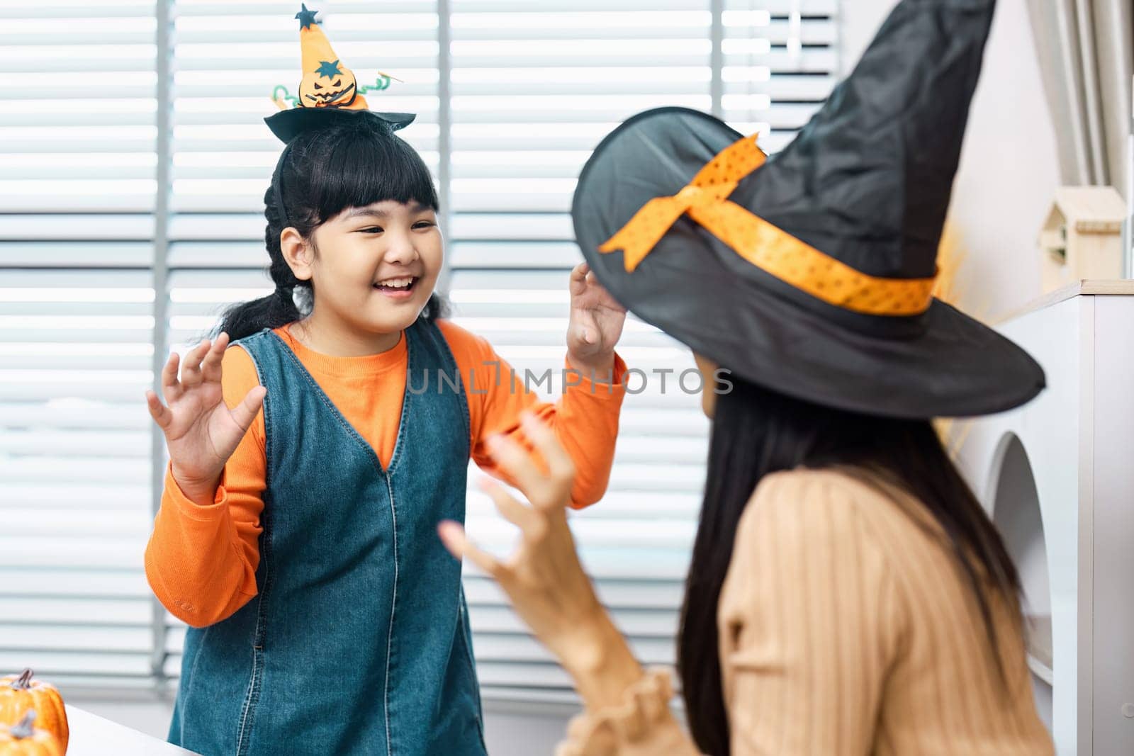Kids enjoying Halloween festivities indoors, dressed in costumes and engaging in playful activities with festive decorations.