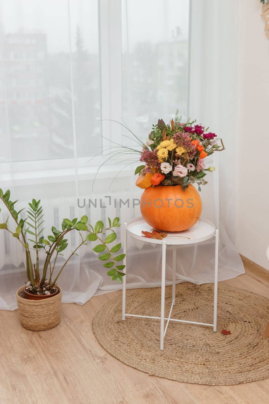 Flower arrangement in a pumpkin, autumn interior decor. Creating handmade autumn decor