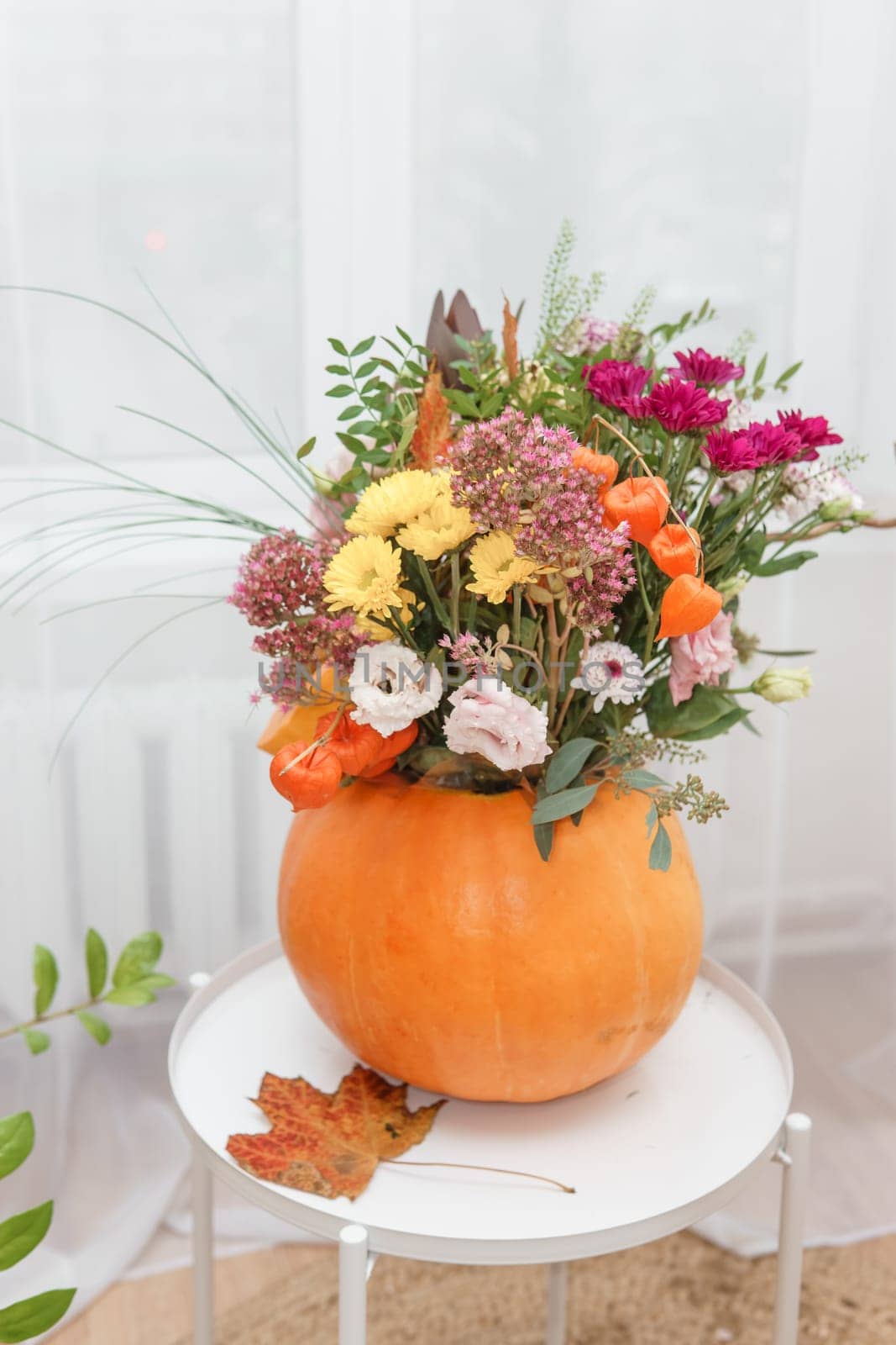 Flower arrangement in a pumpkin, autumn interior decor. Creating handmade autumn decor