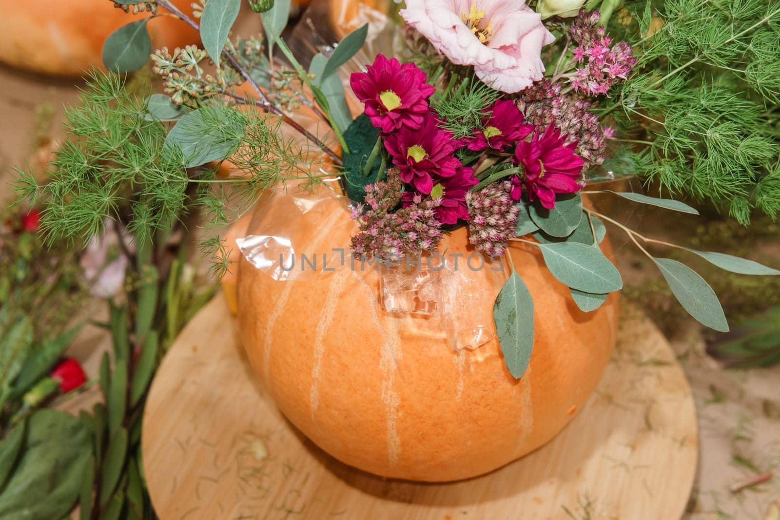Flower arrangement in a pumpkin, autumn interior decor. Creating handmade autumn decor