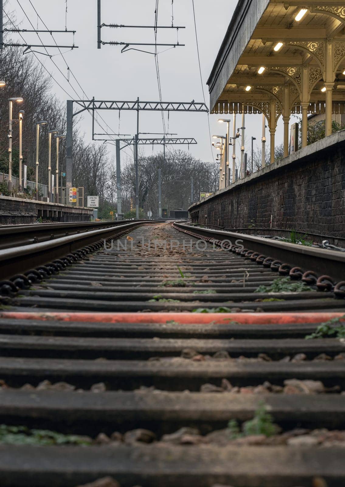 London, UK - Dec 25, 2023 - Railway iron rails from the low perspective. Railroad tracks with limited depth of focus, The Railway system with Metal frames of Train platform, Railroad track rails, Train tracks, Railway station, Space for text, Selective focus.