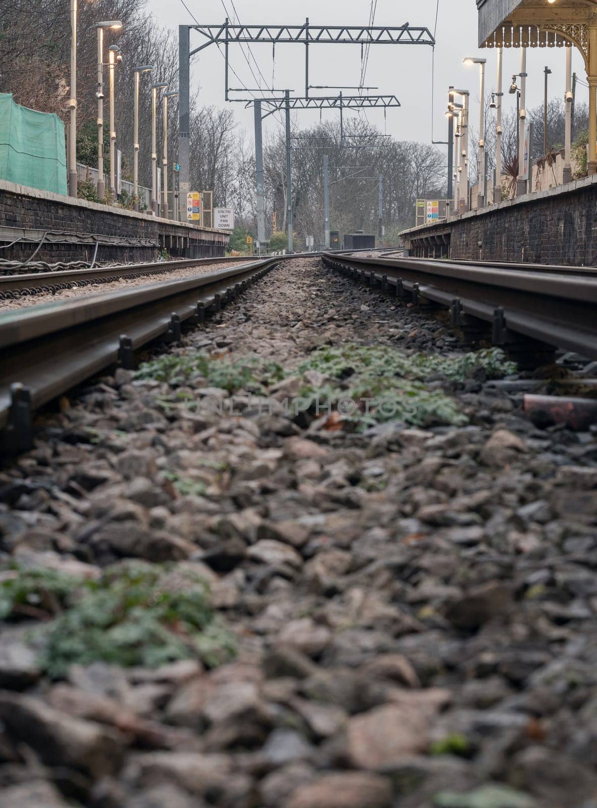 London, UK - Dec 25, 2023 - Railway iron rails from the low perspective. Railroad tracks with limited depth of focus, The Railway system with Metal frames of Train platform, Railroad track rails, Train tracks, Railway station, Space for text, Selective focus.