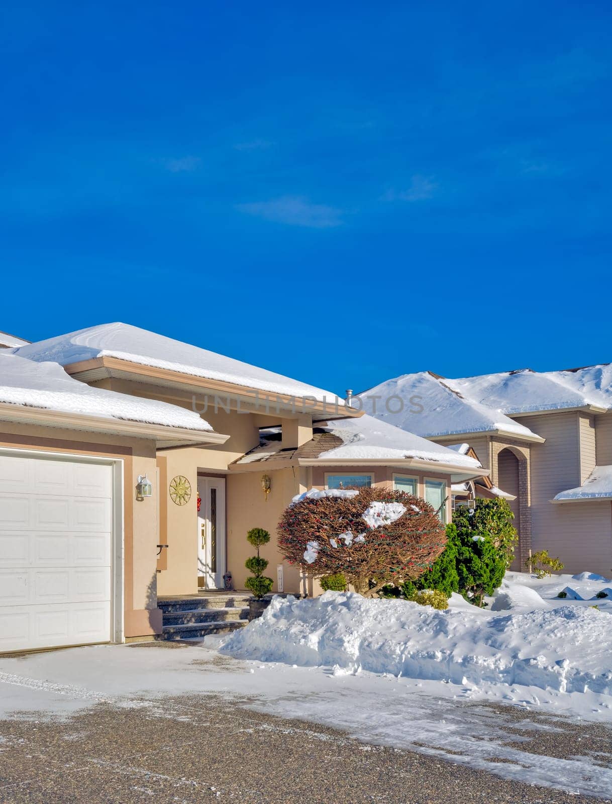 Entrance of luxury house with driveway and front yard in snow. Winter season in canadian suburb