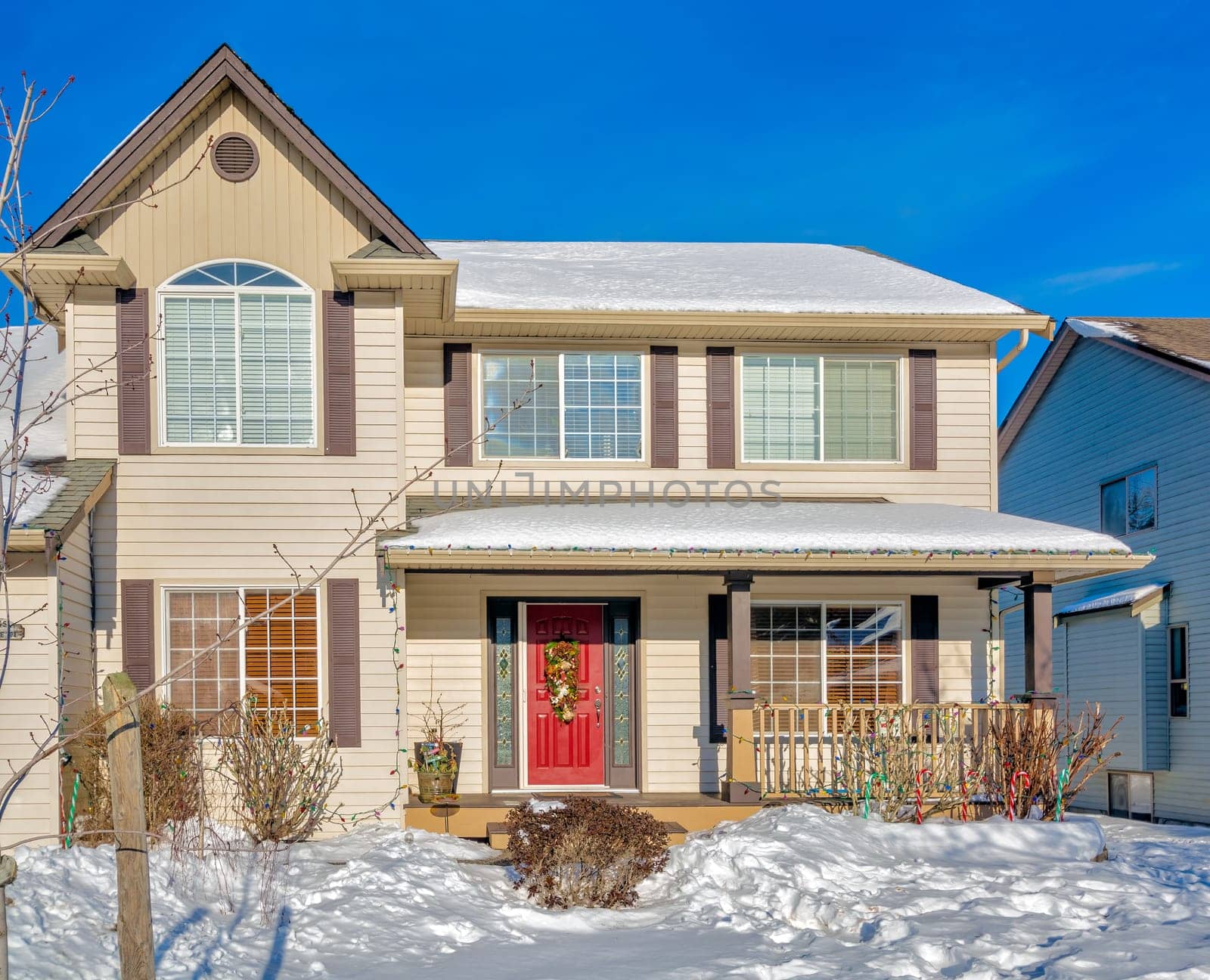 Luxury residential house with front yard in snow. Femily house decorated for christmas celebration on winter sunny day