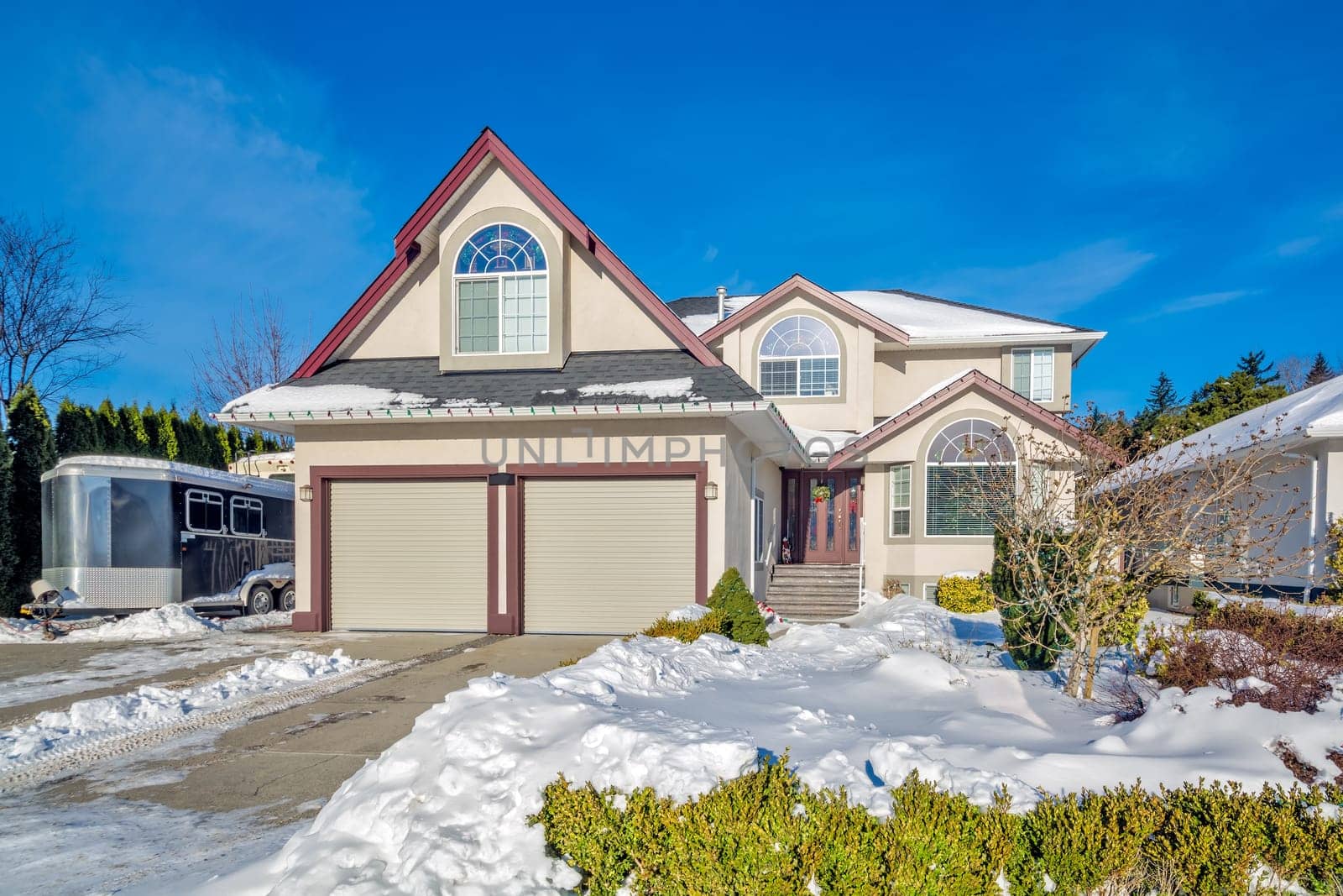 Luxury residential house with double garage on winter season. Family house with driveway and front yard in snow on winter sunny day