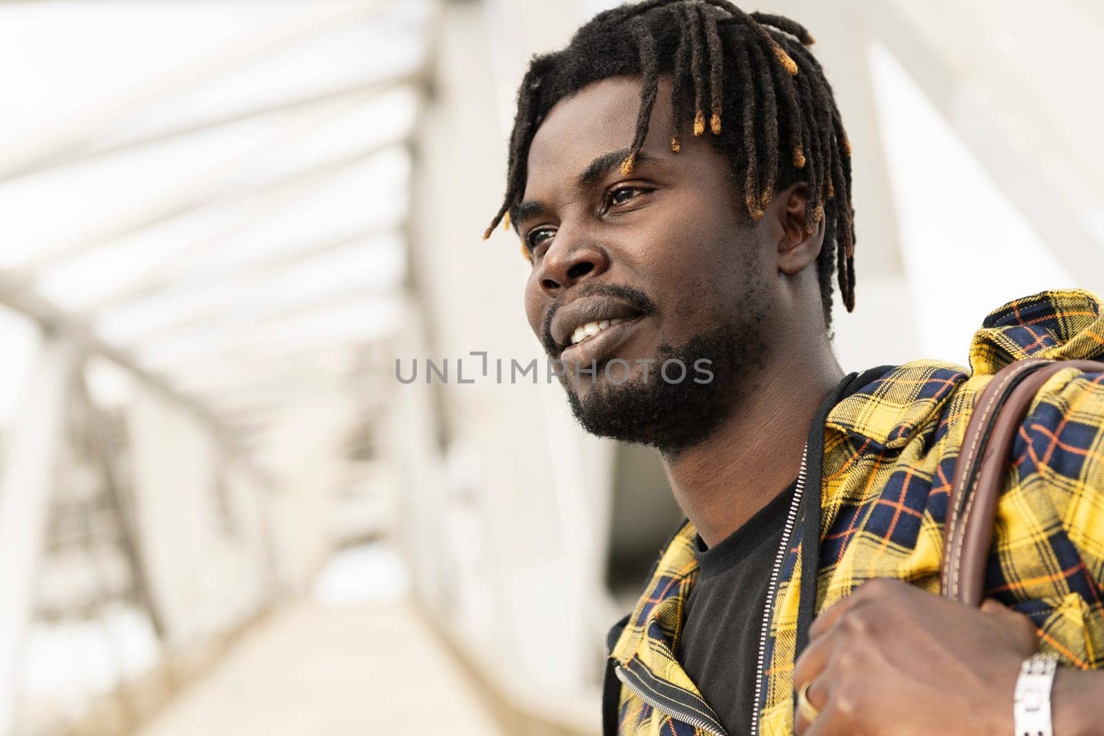portrait of a young african man passing through a modern metal structure to access to the airport, lifestyle and travel concept
