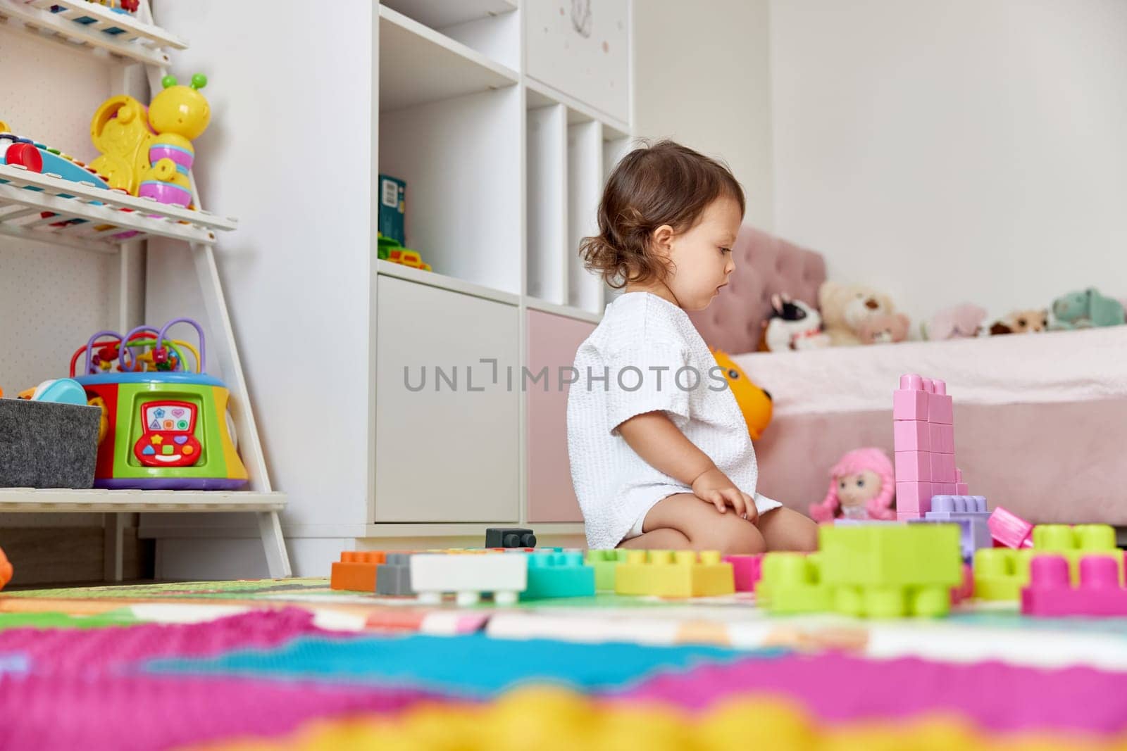 cute baby girl playing with colorful toys bricks at home