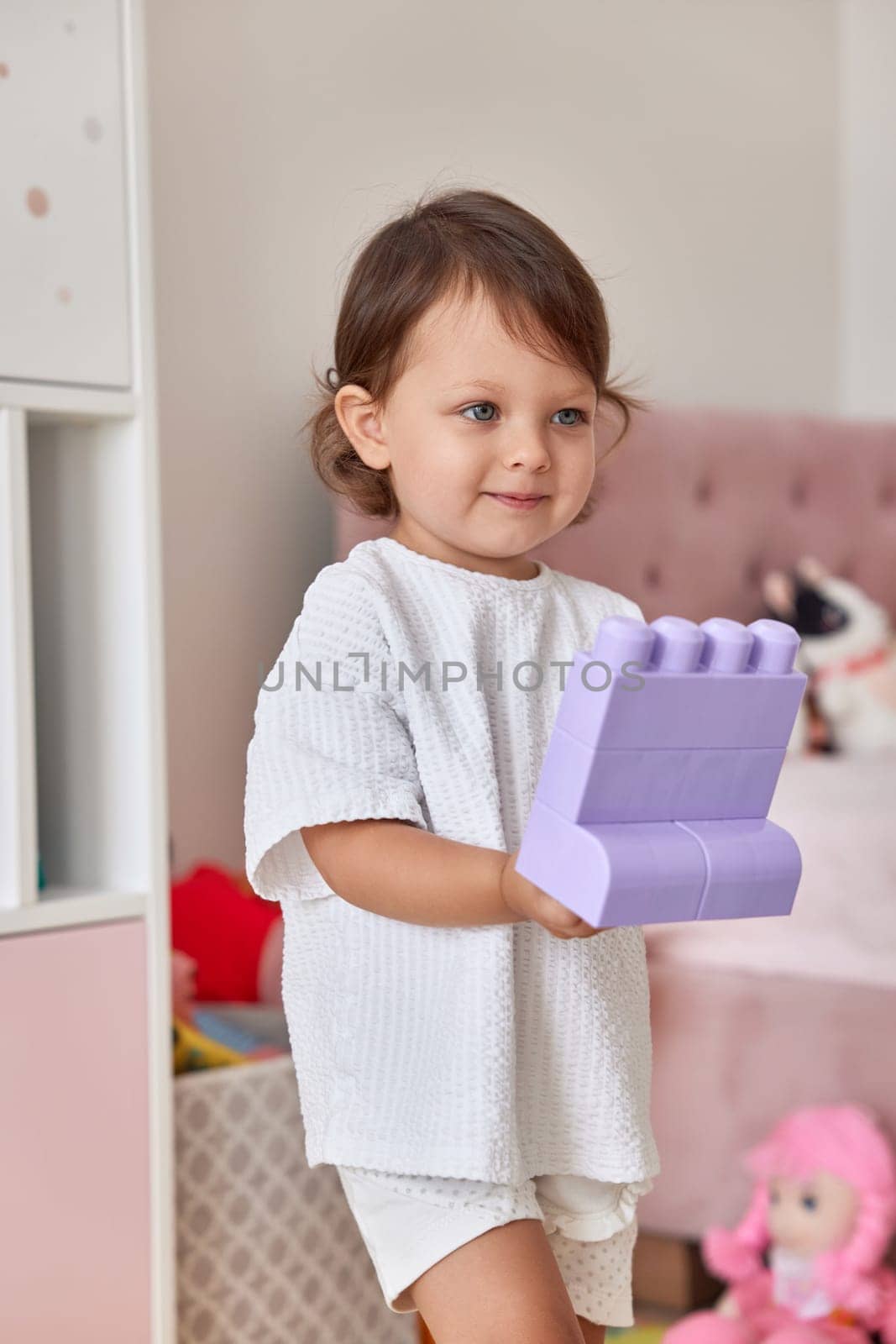 cute baby girl playing with colorful toys bricks at home