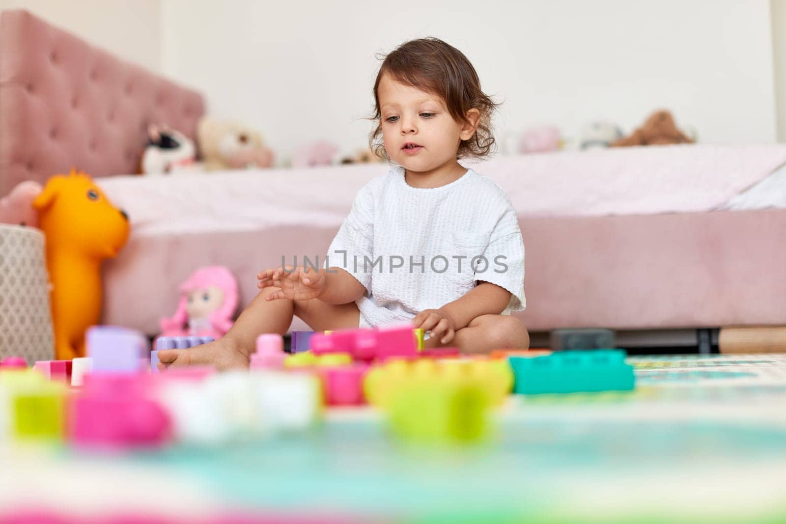 adorable baby girl playing with colorful toys bricks in her room
