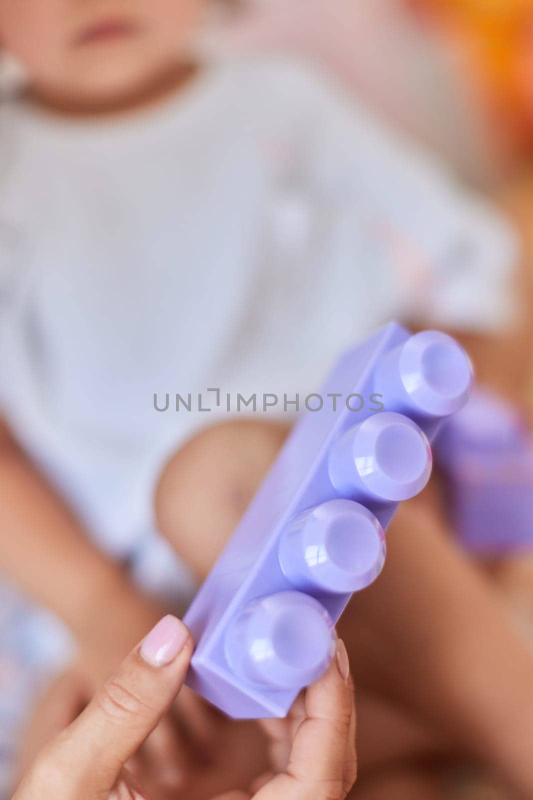 mom showing her little child girl purple plastic building toy block