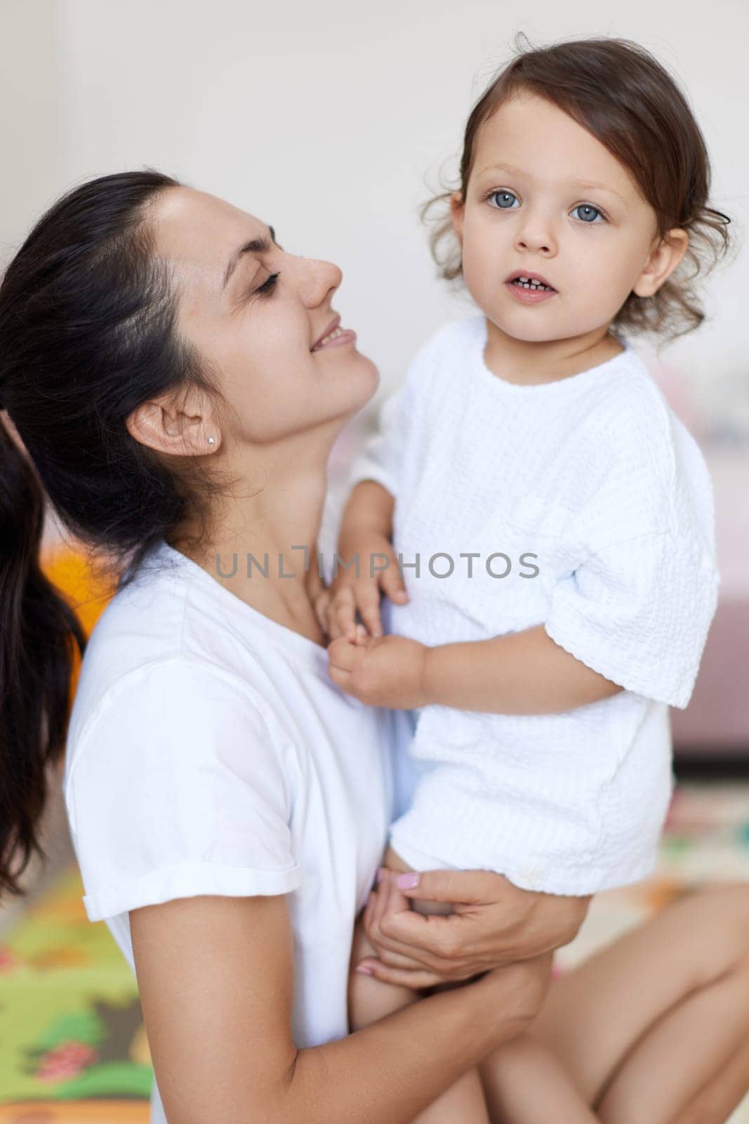 happy mother with cute baby girl in white t-shirt having fun together