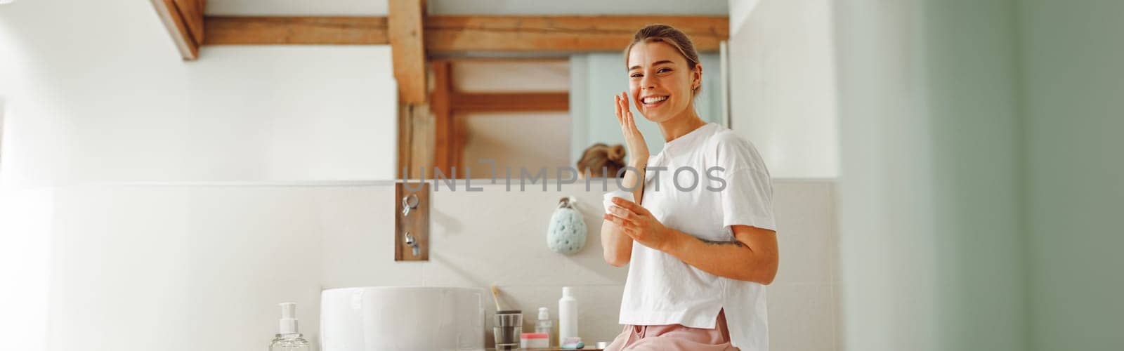Young woman holding jar with skincare cream in hands. Home beauty routine