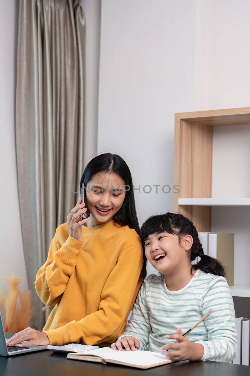 A joyful mother and daughter bonding at home, sharing a moment of laughter and happiness while working on a project together.