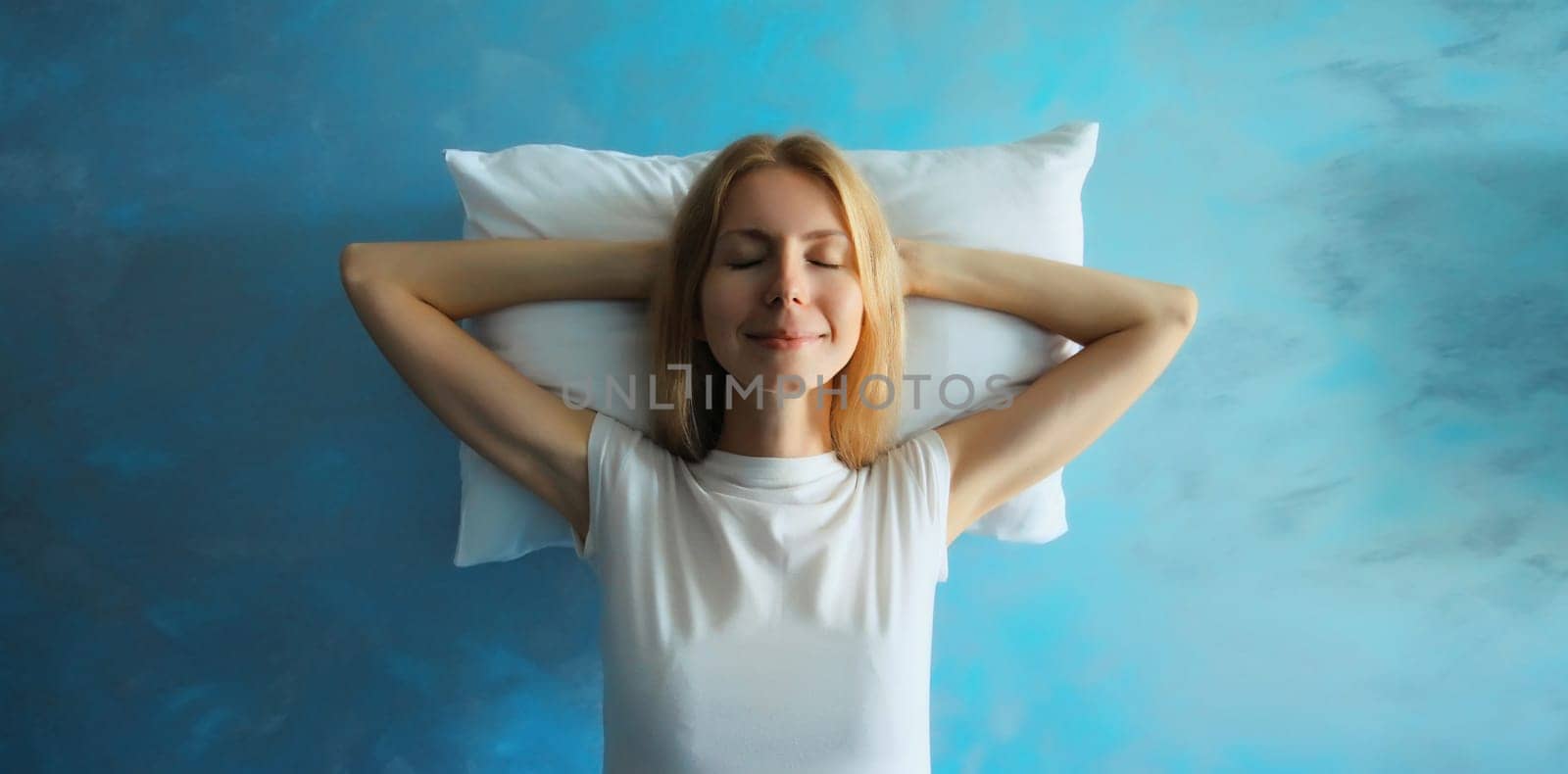 Healthy sleep, happy relaxed sleepy young woman on white soft comfortable pillow imagining that she is lying on the bed