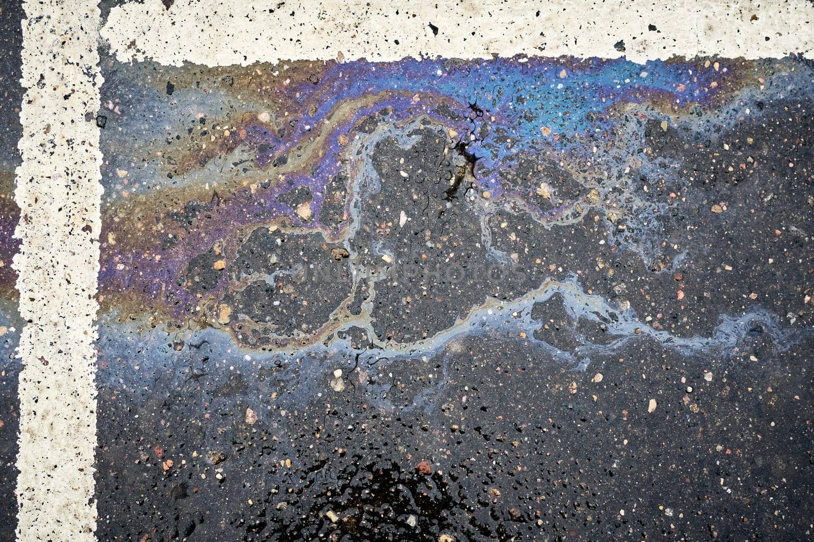 Oil Residue on Saturated Asphalt in a Parking Space with Division Markings.