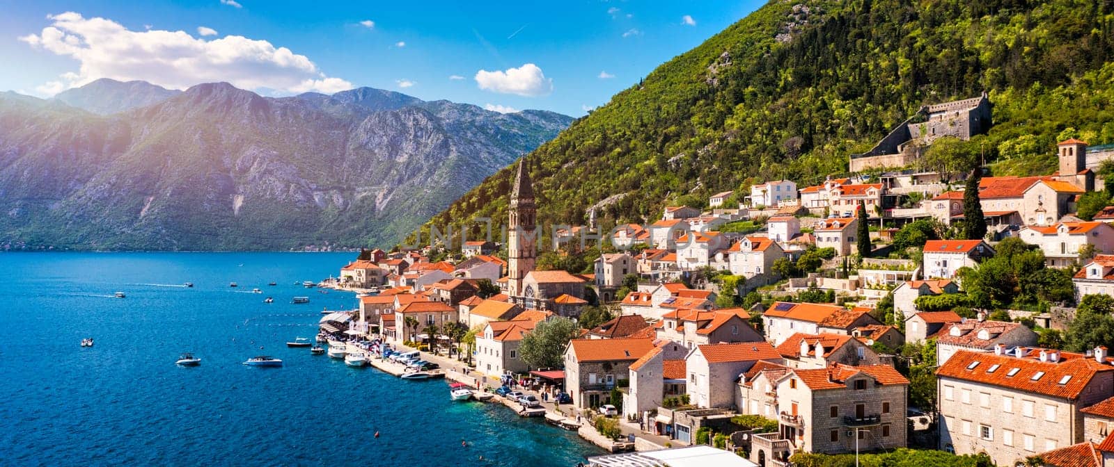 View of the historic town of Perast at famous Bay of Kotor on a beautiful sunny day with blue sky and clouds in summer, Montenegro. Historic city of Perast at Bay of Kotor in summer, Montenegro.