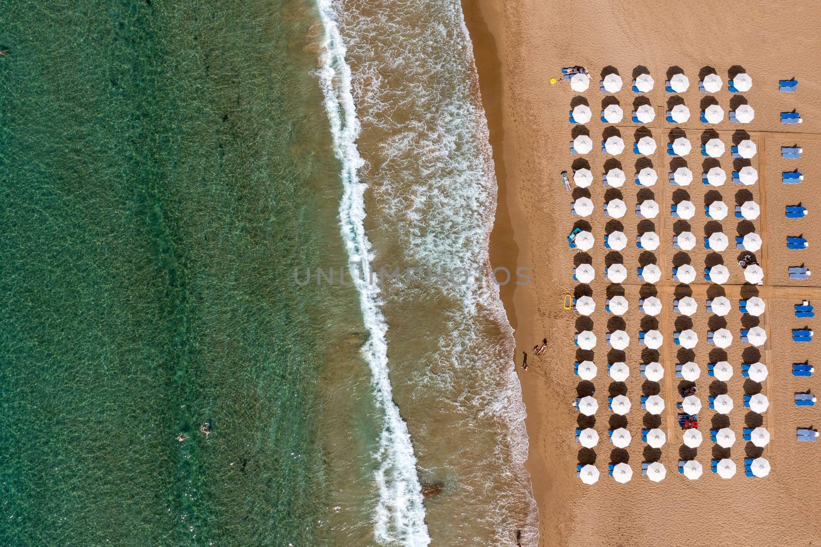 Concept of summer vacation. View from above, stunning aerial view of an amazing beach with beach umbrellas and turquoise clear water. Top view on a sun lounger under an umbrella on the sandy beach