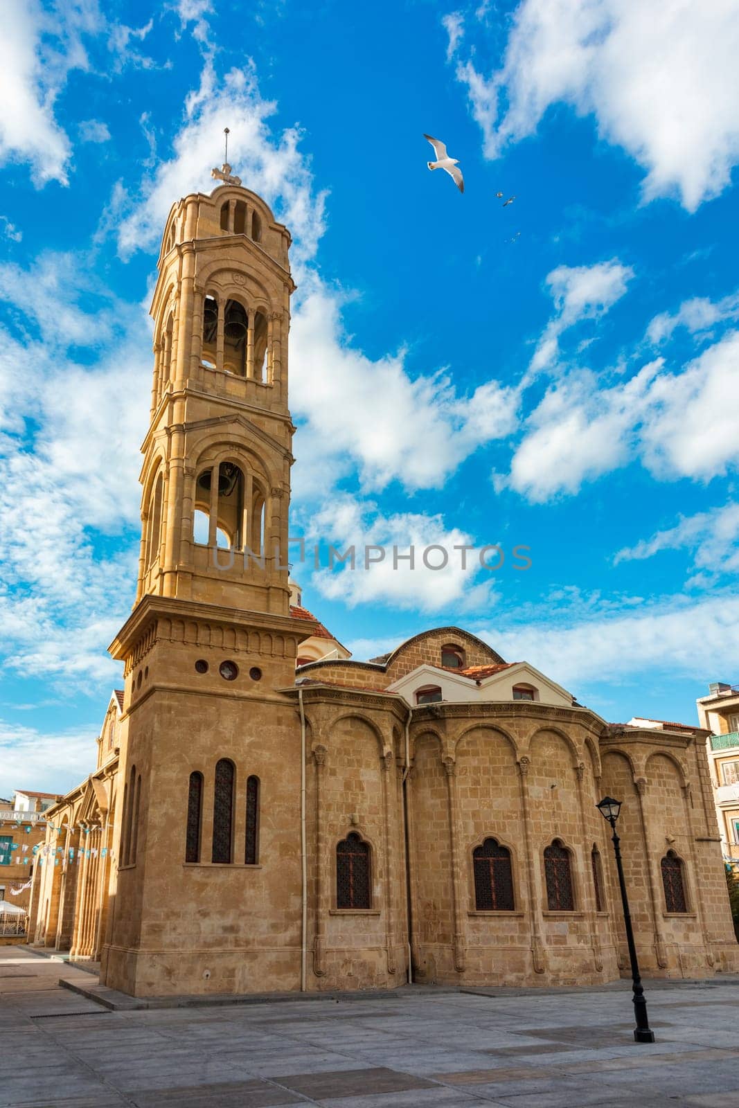 A small building with a blue door sits in front of a large Mosque with a tall tower in Nicosia, Cyprus. Beautiful street with old architecture in Nicosia, Cyprus.