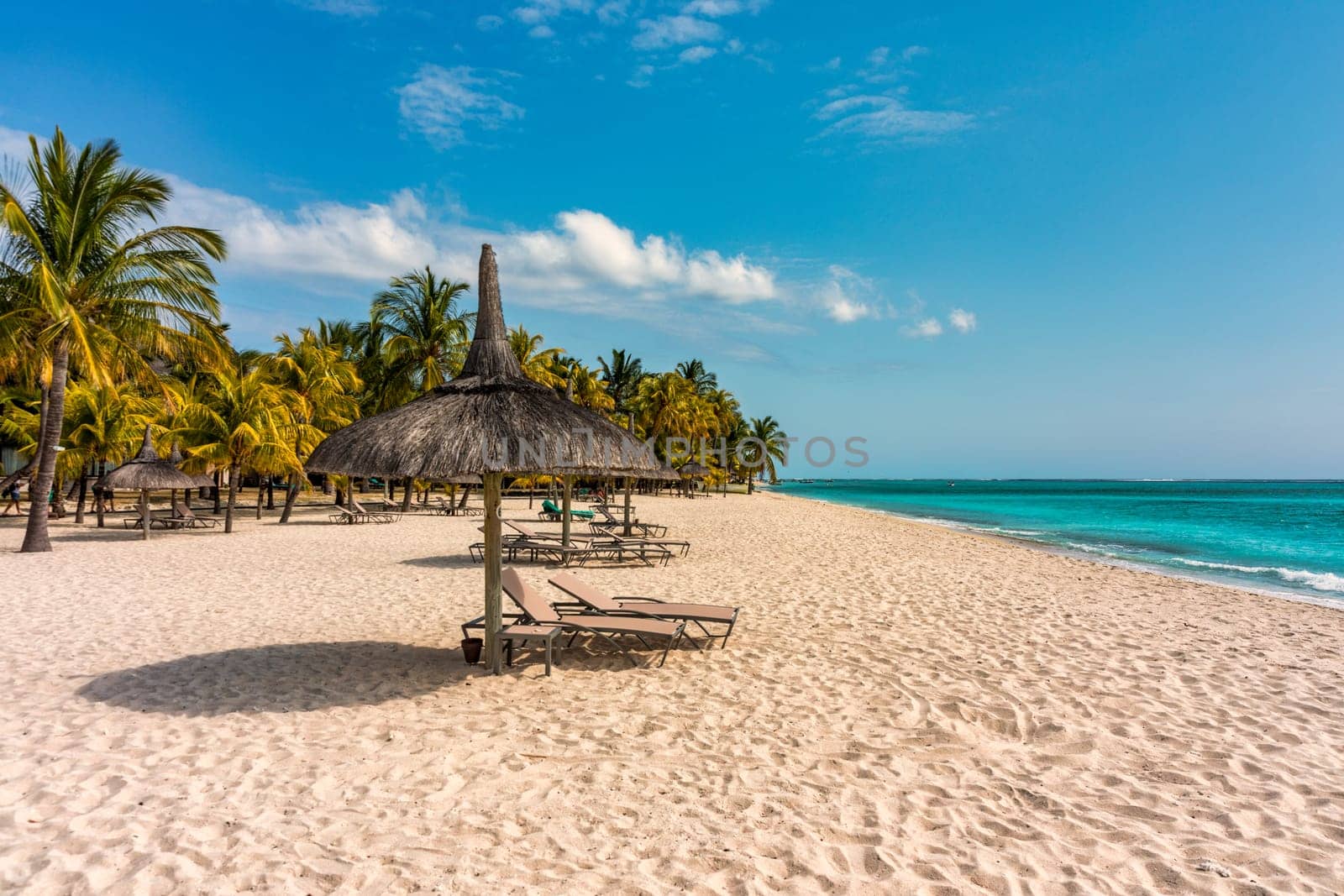 A beach with palm trees and umbrellas on Le morne Brabant beach in Mauriutius. Tropical crystal ocean with Le Morne beach and luxury beach in Mauritius. Le Morne beach with palm trees, white sand and luxury resorts, Mauritius.
