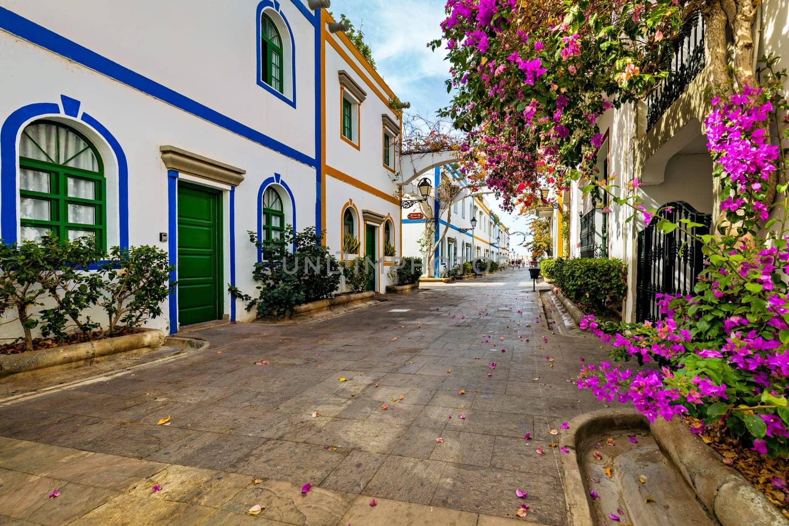 Street with blooming flowers in Puerto de Mogan, Gran Canaria, Spain. Favorite vacation place for tourists and locals on island. Puerto de Mogan with lots of bougainvillea flowers, Canary Island.