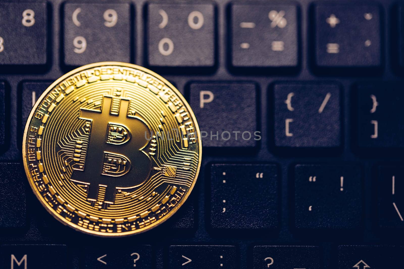 Bitcoin on compuer keyboard in background, symbol of electronic virtual money and mining cryptocurrency concept. Coin crypto currency bitcoin lies on the keyboard. Bitcoin on keyboard.