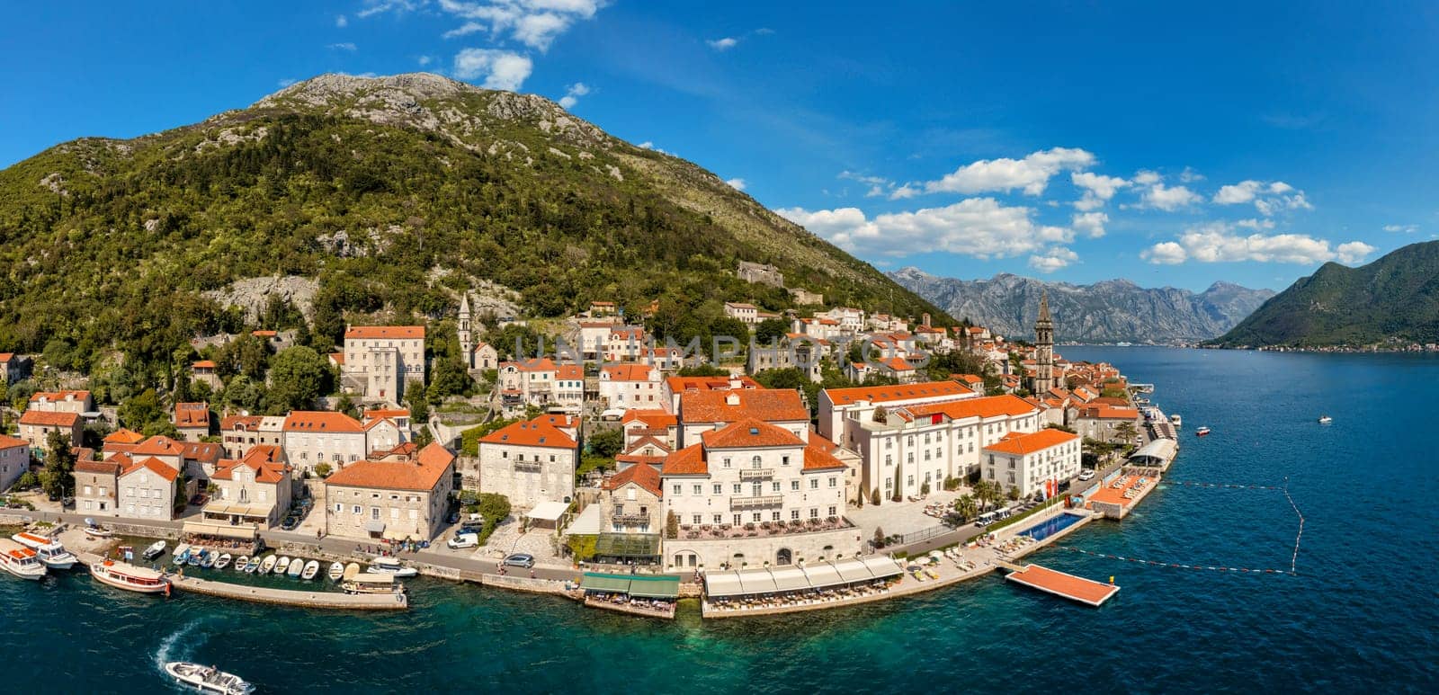 View of the historic town of Perast at famous Bay of Kotor on a beautiful sunny day with blue sky and clouds in summer, Montenegro. Historic city of Perast at Bay of Kotor in summer, Montenegro.