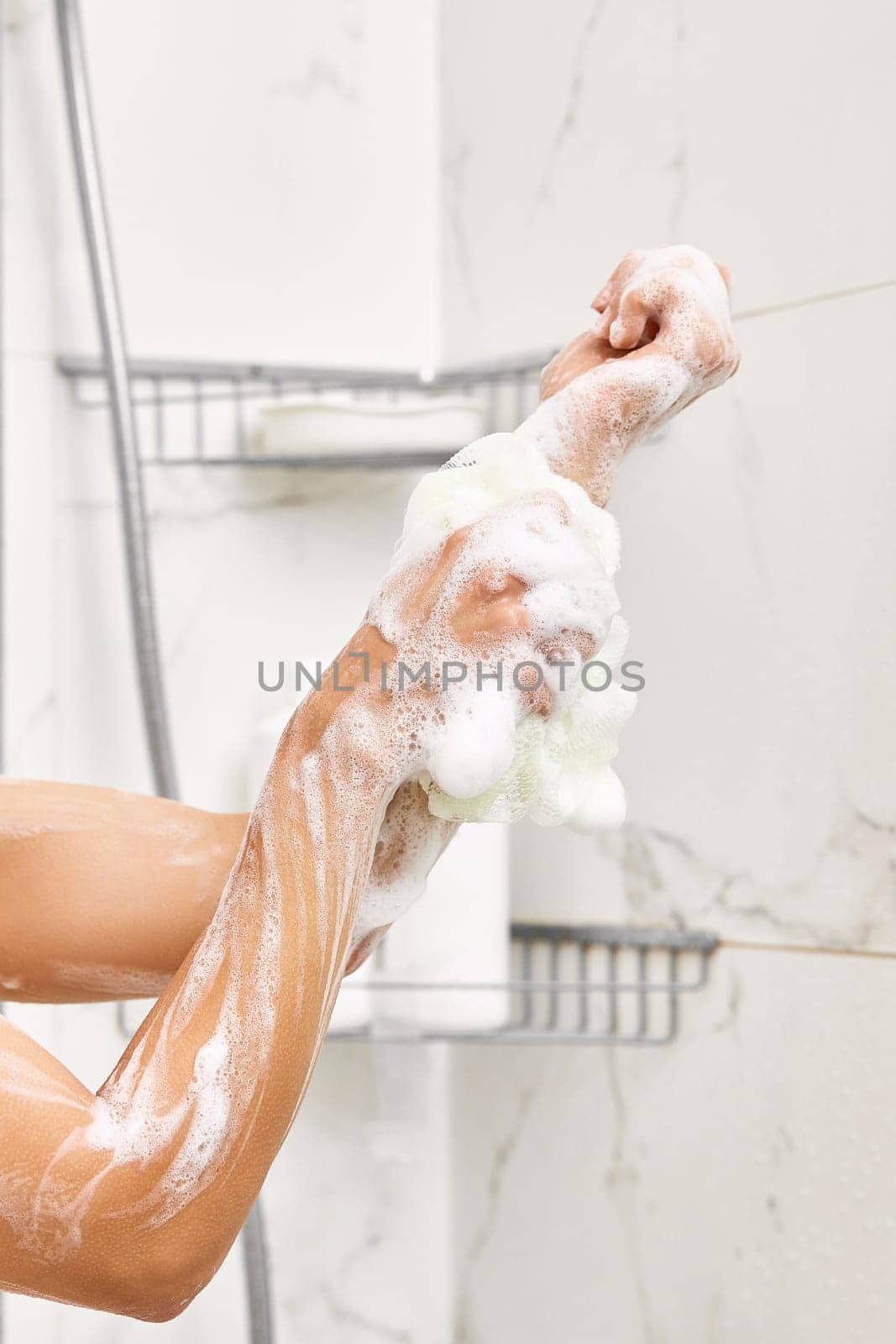 Woman washing her hands with foam bubbles and bath sponge in bathroom. close-up.