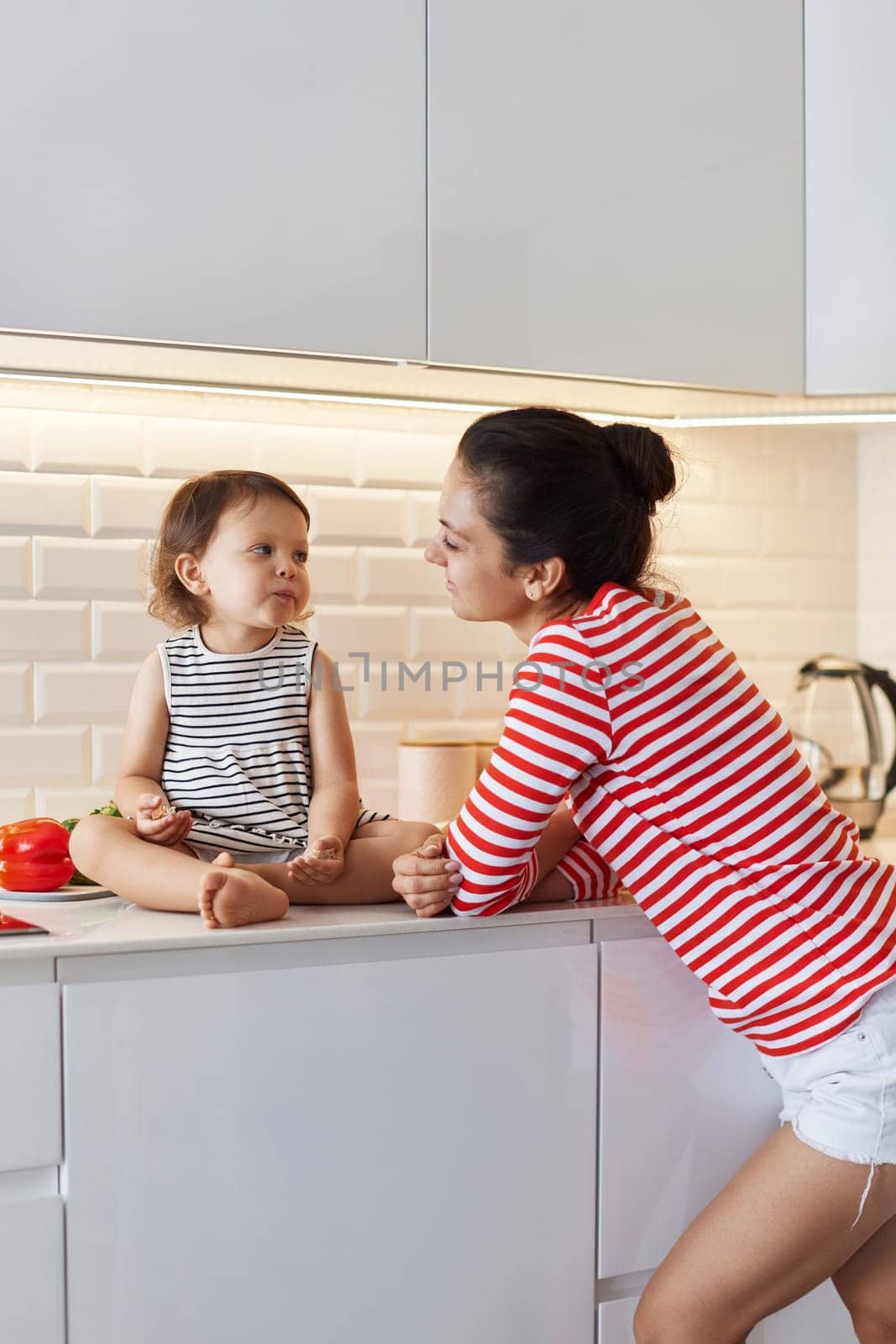 happy mother and her cute little girl enjoy preparing breakfast in white kitchen, happy moment together