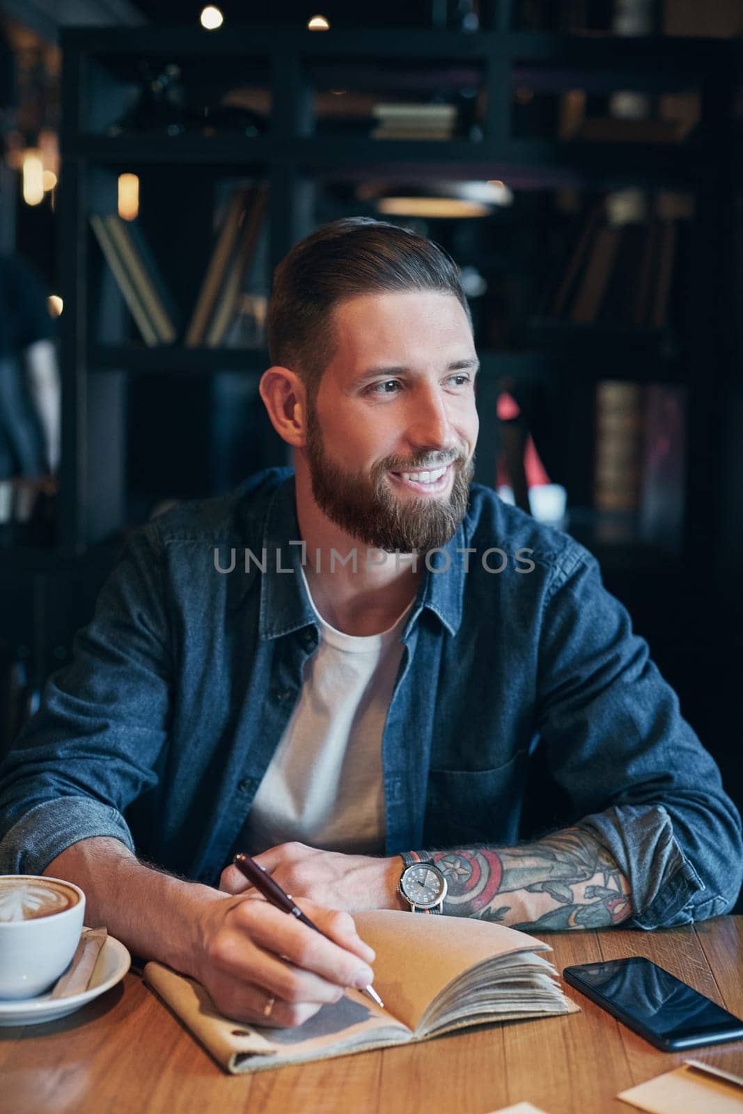 Man hand with pen writing on notebook on a wooden table. Man working at coffee shop