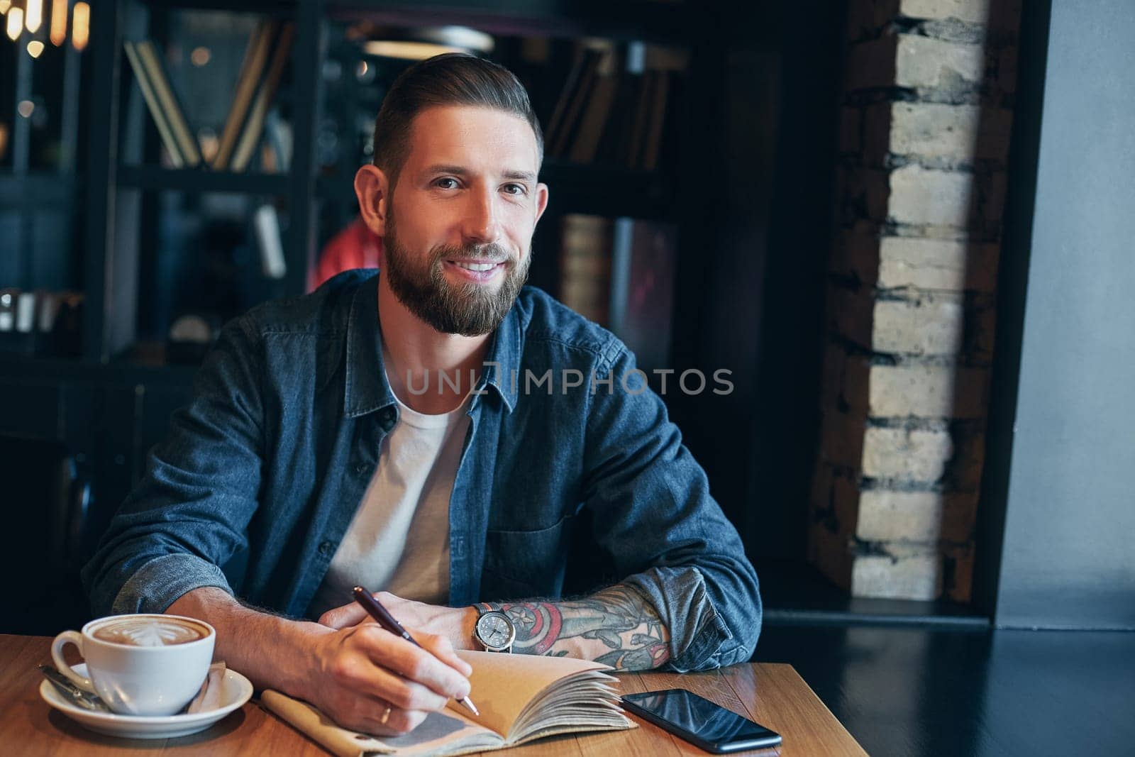 Man hand with pen writing on notebook on a wooden table. by nazarovsergey